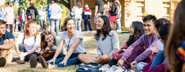 A group of students socializing together while sitting in the grass