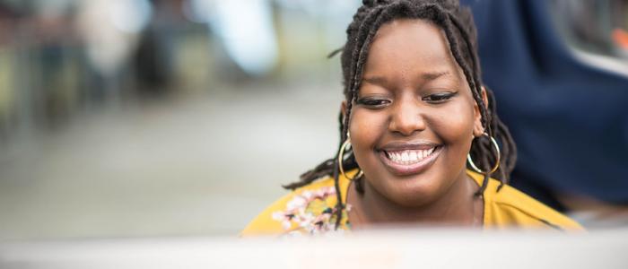Female UBC Black student smiling at laptop monitor